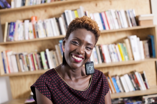 Journalist and filmmaker Rokhaya Diallo fears French President Emmanuel Macron's forthcoming "separatism law" will only create more division. A Black woman with short hair wears earrings and a black and red blouse and smiles warmly in front of a large bookshelf.