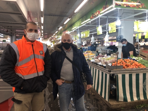 Abdel Hakim (left) and his friend Djilali, say the French government should be less preoccupied with the country's Muslim population and focus on responding to the coronavirus pandemic. A man wearing an orange vest stands near his older friend at an indoor market