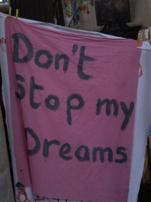 A banner inside a church occupied by migrants reads "Don't stop my dreams." A pink sign reads "Don't stop my dreams" inside a church