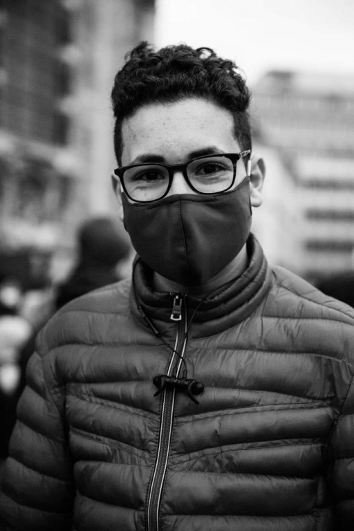 Sixteen-year-old Mohammed Amine has been sleeping inside a church for over a month to protest migrant conditions in Belgium. Sixteen-year-old Mohammed Amine wears glasses, a face mask and puffy jacket.
