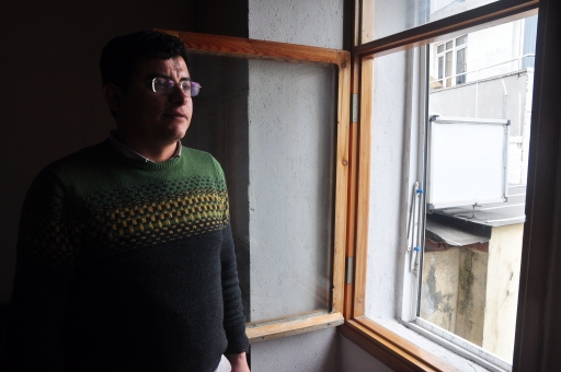 Sadık Topaloğlu stands in the Istanbul office of the Mesopotamia Agency, where he serves as bureau chief. A man stands by the window.