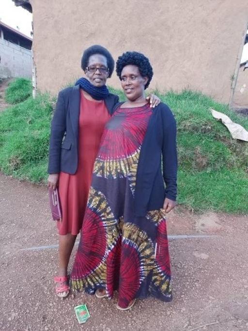 Mukobwajana Kandenzi, 58, (right) from Democratic Republic of Congo, poses for a photo at the Gihembe refugee camp in Rwanda. Two women pose together in Rwanda for a photo wearing reddish traditional clothing.