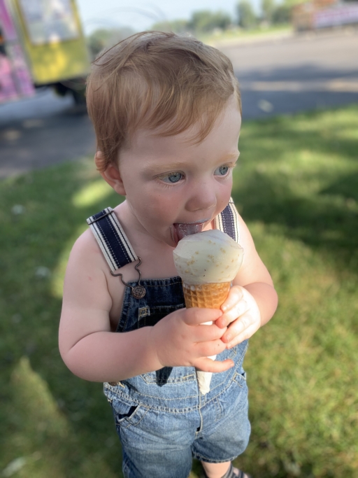 Edison Tiessen is now 2 years old, and he doesn't yet know how to write. But he has devoted readers. A small toddler eats an ice cream cone in overalls