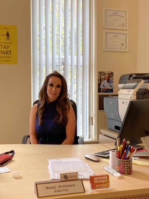 Mandy McDermott is senior psychotherapist at Compass Counseling, on the predominantly Protestant Shankill Road area of west Belfast. A white woman senior psychotherapist wears a black shirt and sits at a beige desk inside at her office.
