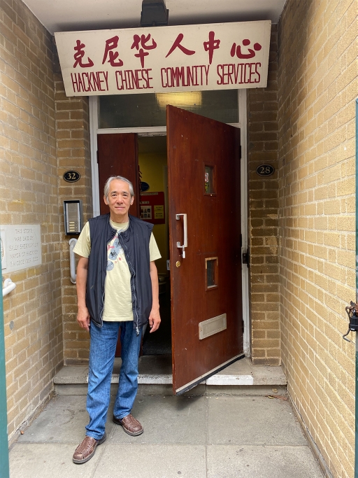 Jabez Lam, manager of the Hackney Chinese Center in east London A man stands in front of a door with the words 'Hackney Chinese Community Services' written above in Chinese and English.