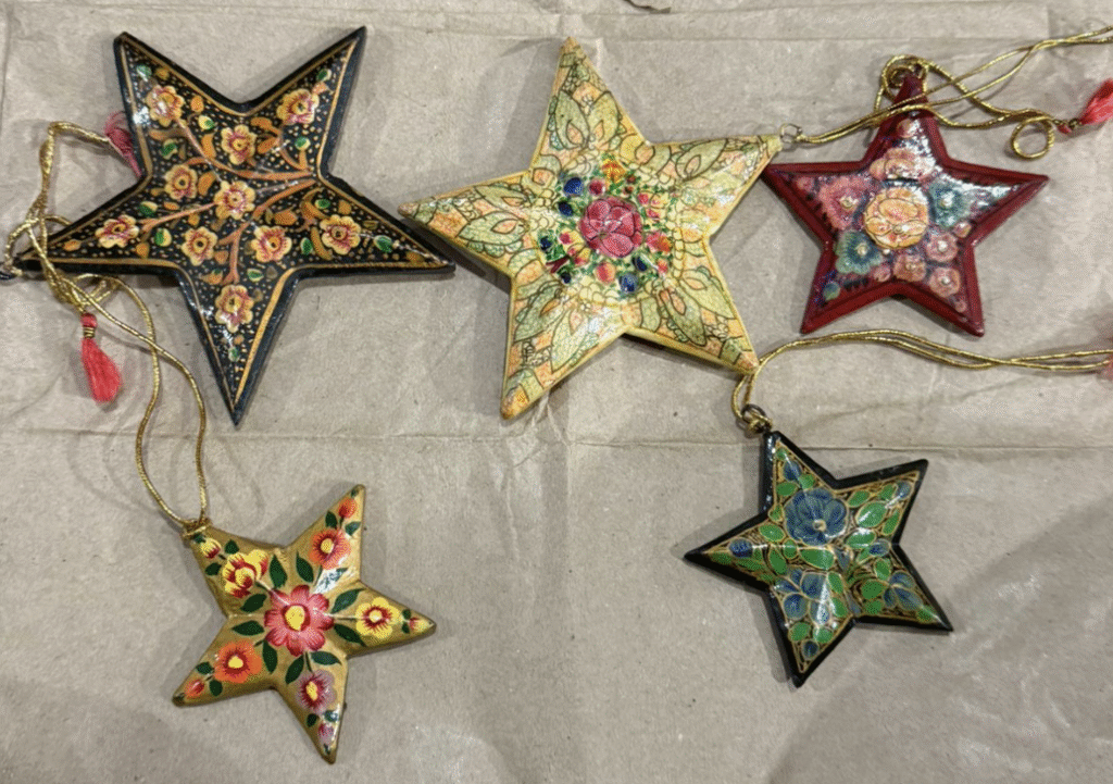Five star-shaped ornaments with intricate floral patterns and vibrant colors, each featuring a unique design, arranged on a light-colored background.