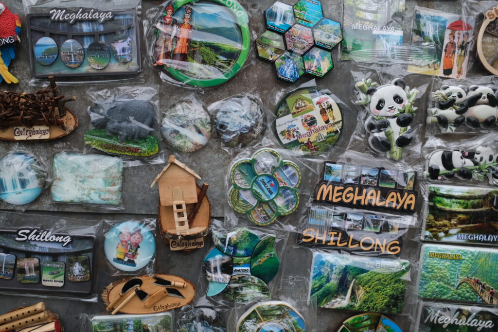 Various Meghalaya souvenirs, including magnets and keychains with images of landscapes, Shillong, and panda figures.