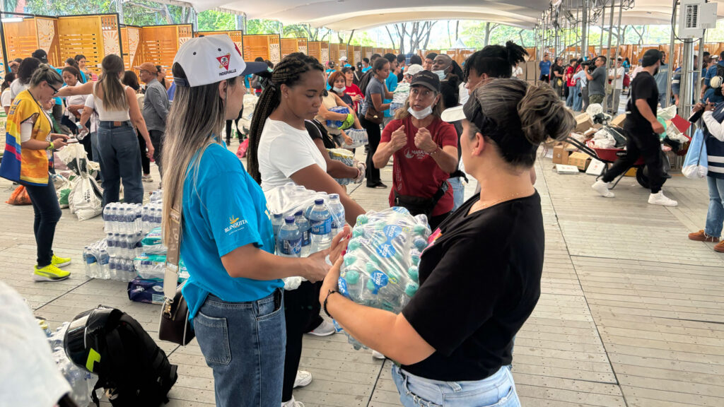 Volunteers distributing cases of bottled water at a busy relief distribution center