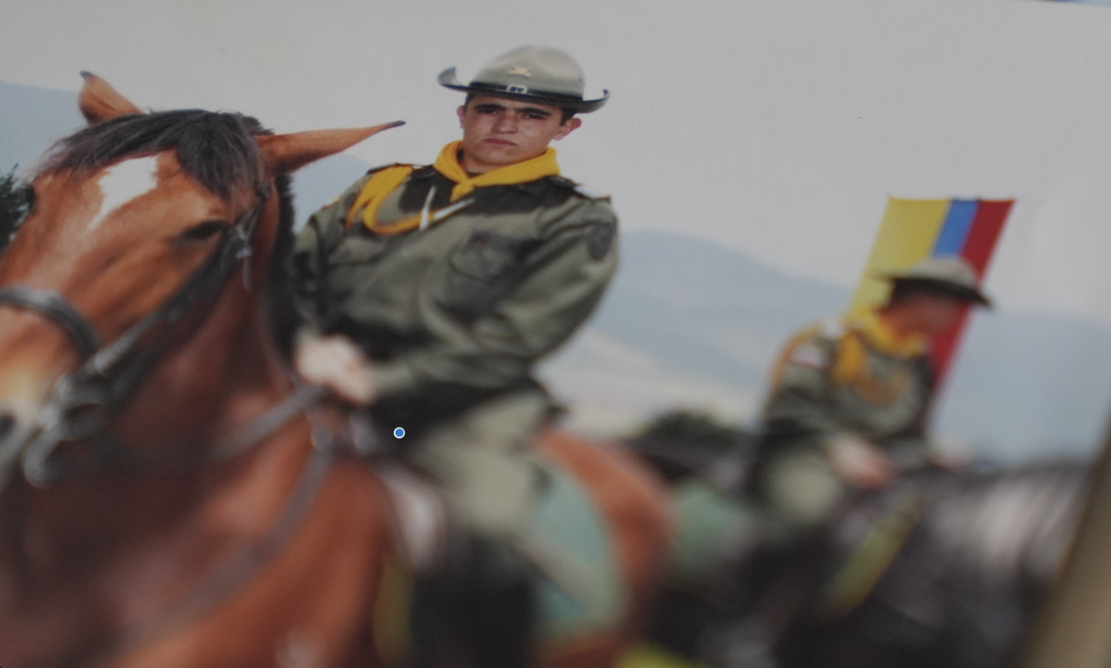 Mounted police officers in campaign hats and olive uniforms on horseback, with a Colombian flag visible in the background